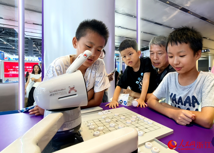五年級(jí)的學(xué)生候晉凱正同機(jī)器人一較棋藝。人民網(wǎng)記者 張麗瑋攝
