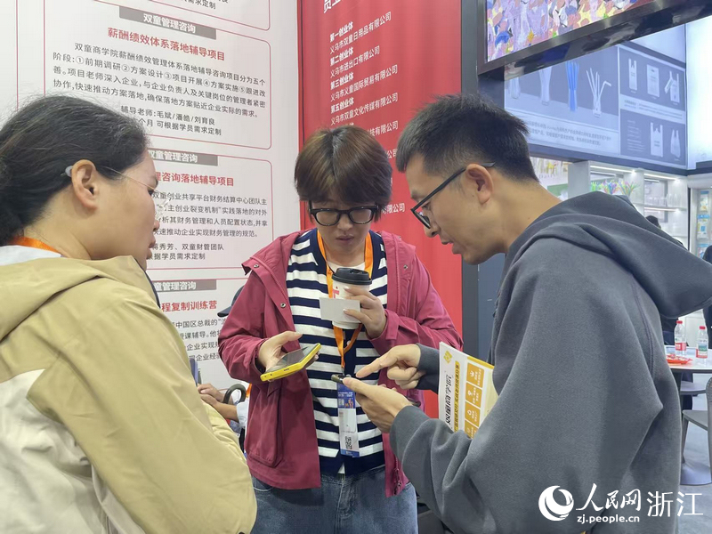 客商與雙童商學(xué)院工作人員互加聯(lián)系方式。人民網(wǎng)記者 王麗瑋攝